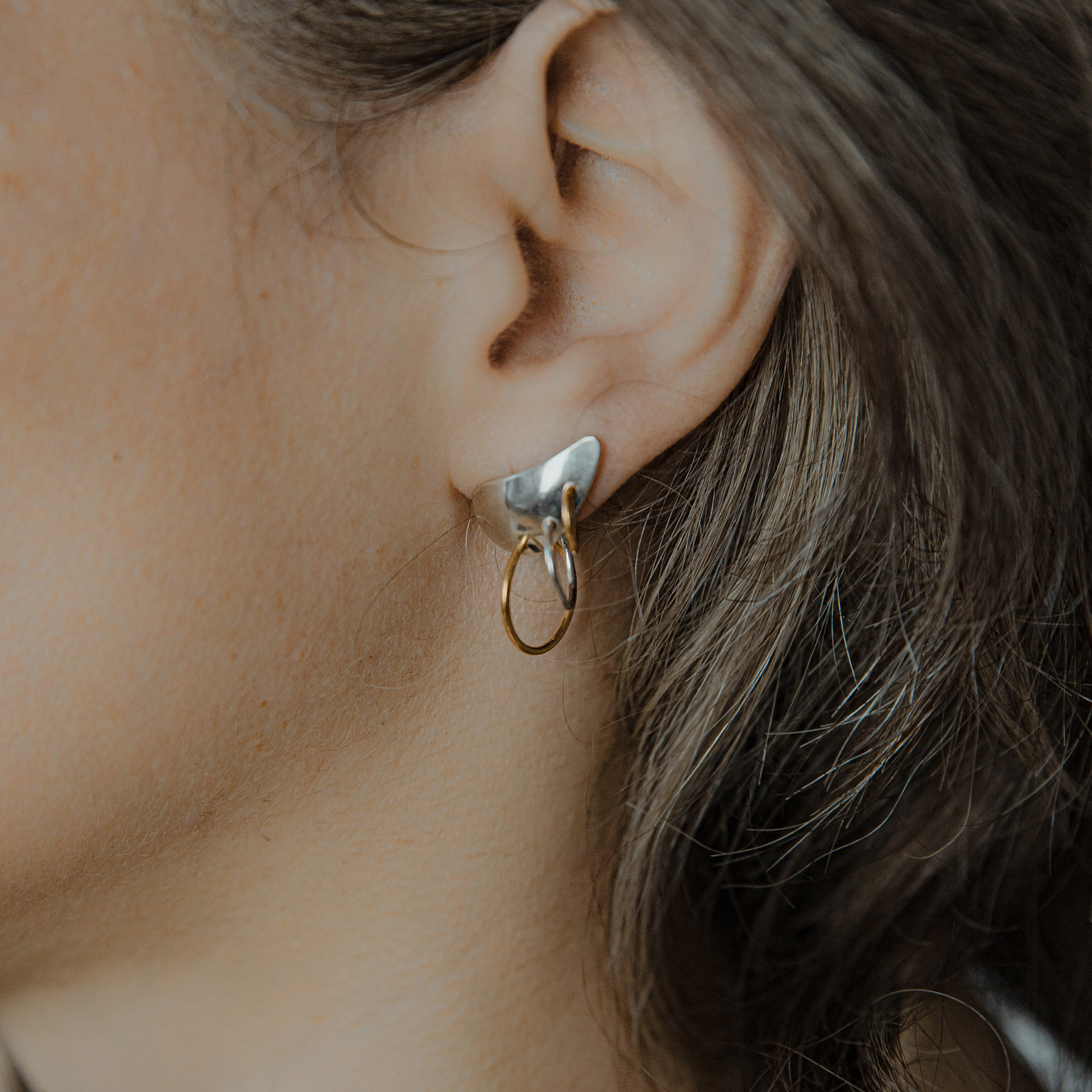 Piasu earrings in silver covering ear lobe with three hoops hanging on it