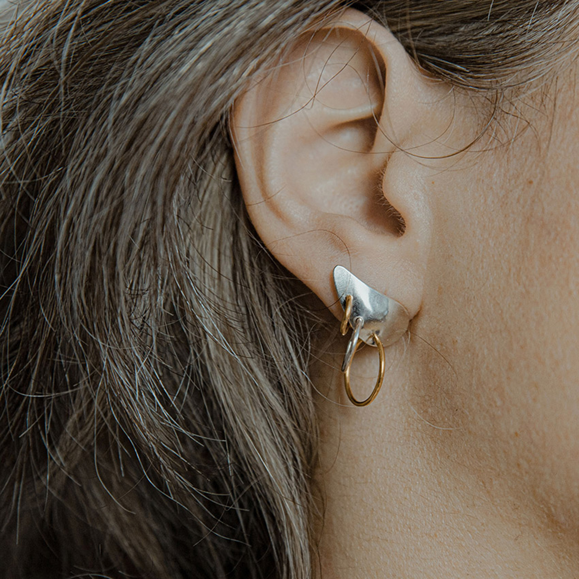 Piasu earrings in silver covering ear lobe with three hoops hanging on it