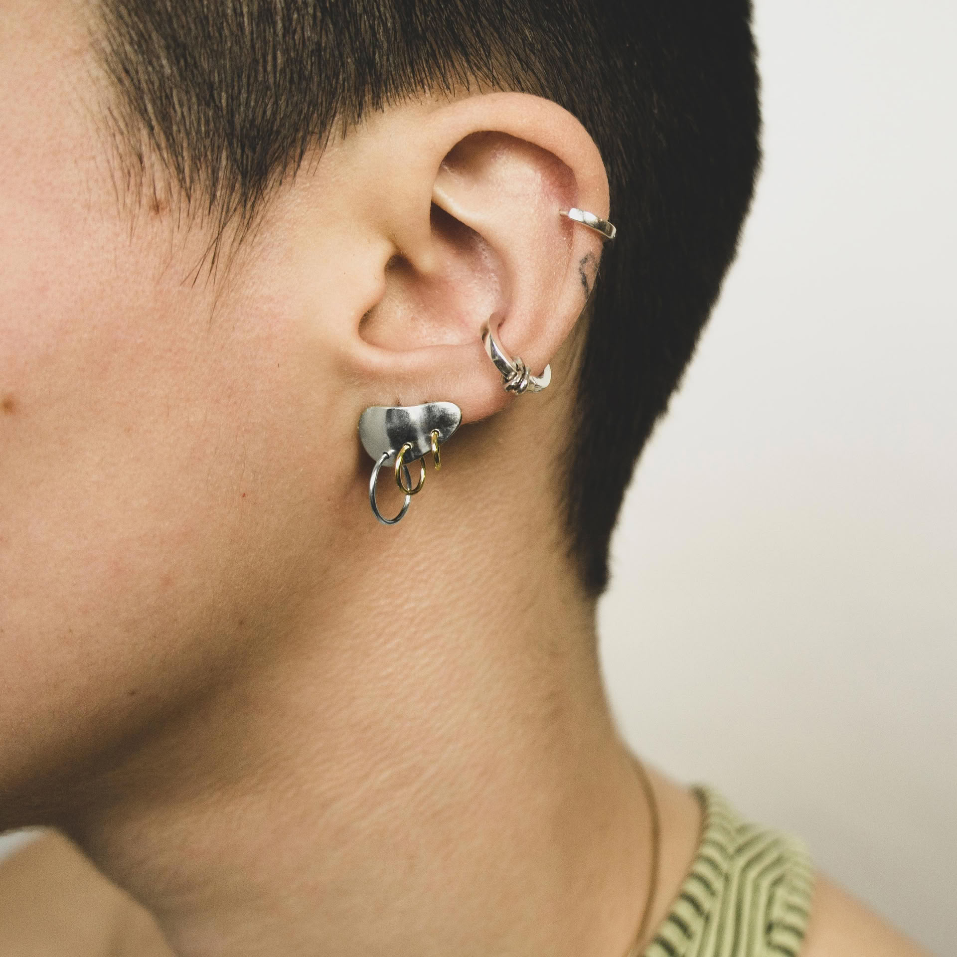 Piasu earrings in silver covering ear lobe with three hoops hanging on it