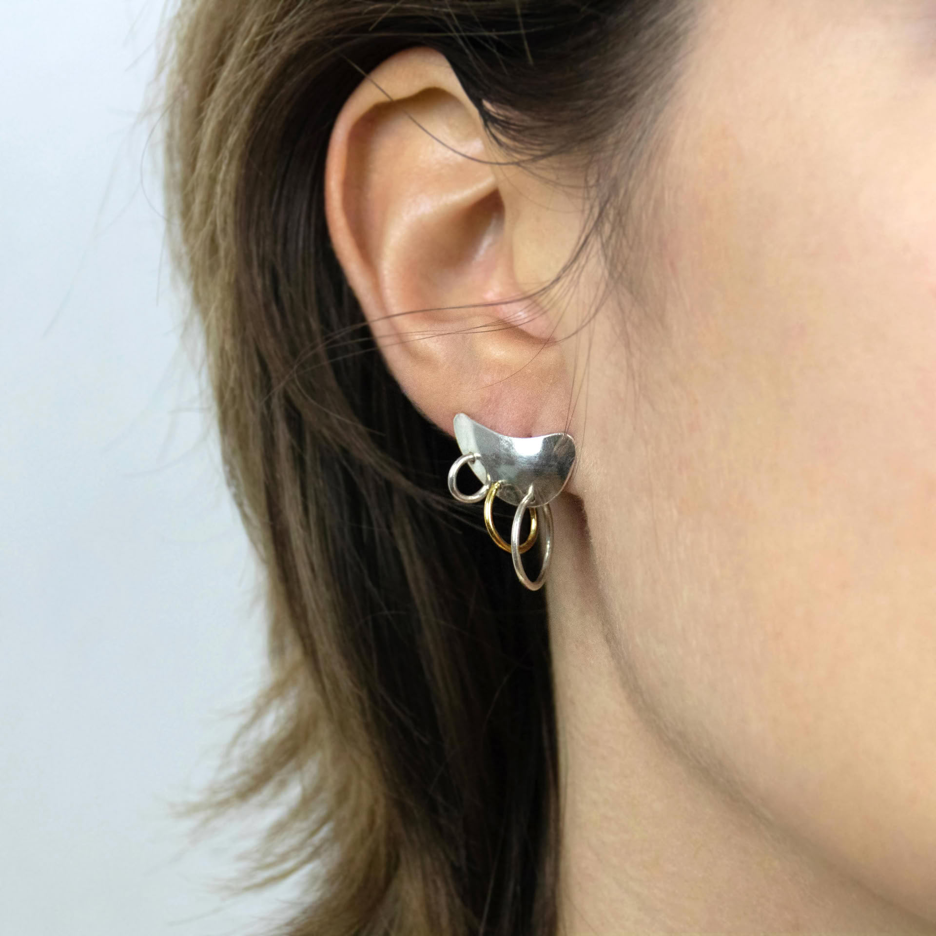 Piasu earrings in silver covering ear lobe with three hoops hanging on it