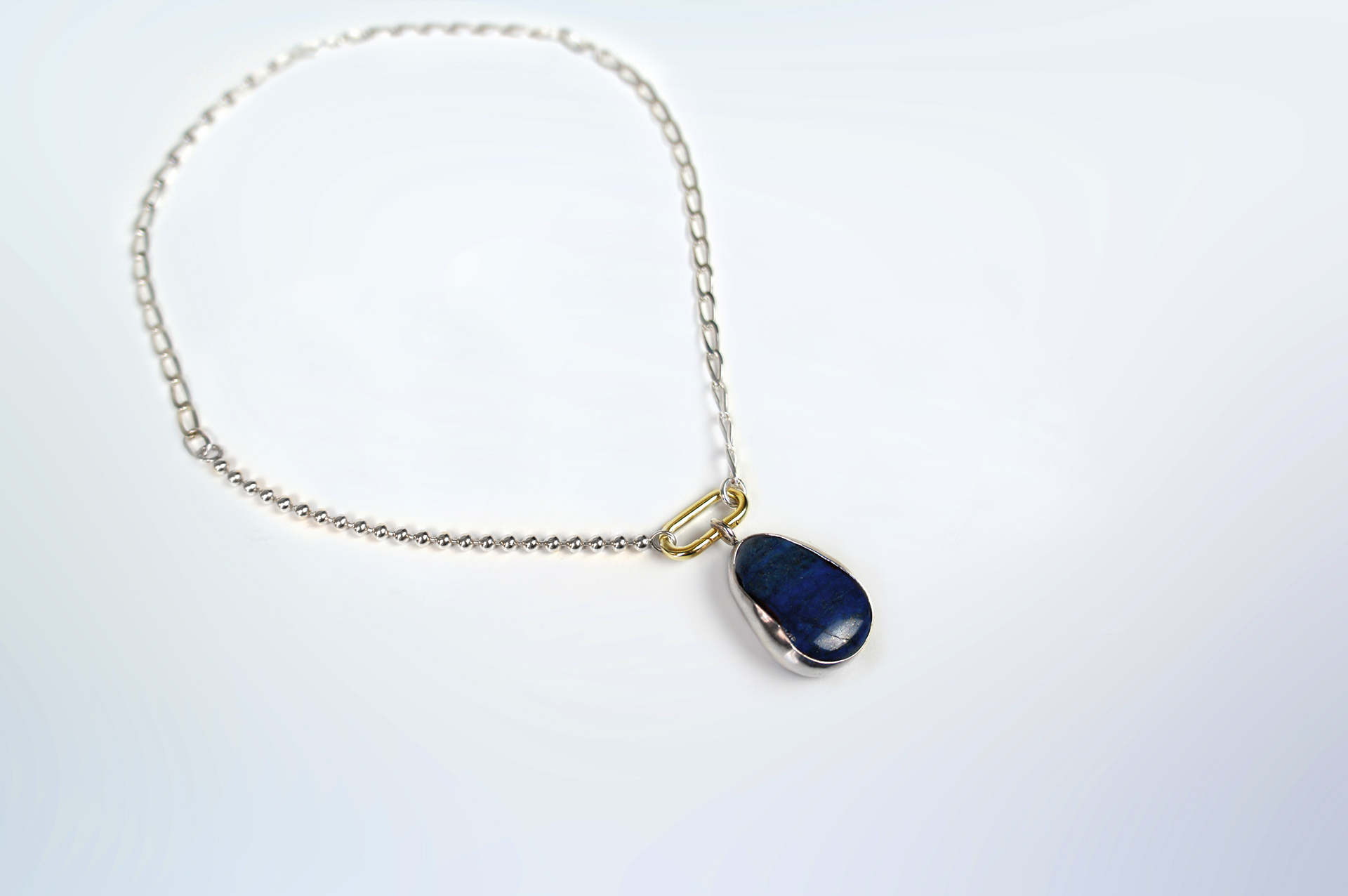 Rokku statement necklace in silver with lapis lazuli stone pendant and gold plated clasp.